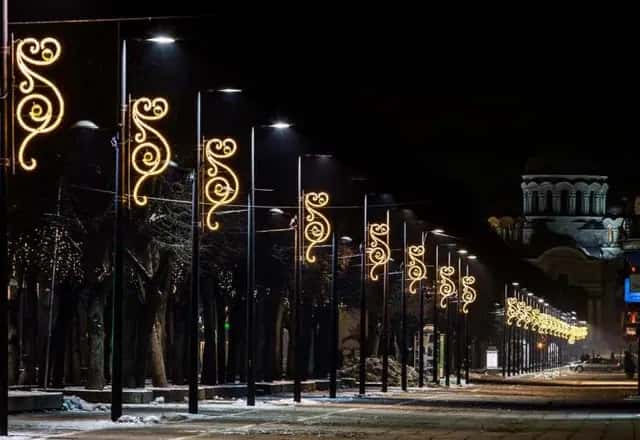 Altın LED sarmal motifleriyle süslenmiş ağaçlı bulvar direkleri, sisli gece