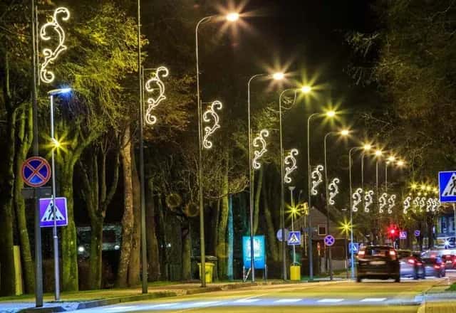 Ağaçlı kaldırım boyunca direklere monte edilmiş kanca formlu LED küre sarmalları, gece