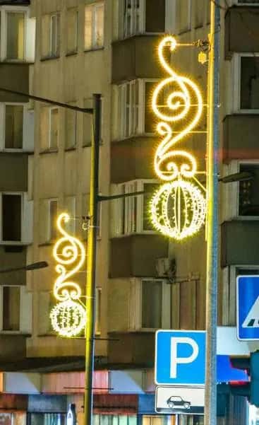 Apartman köşesinde direğe monte edilmiş altın LED küreli sarmal motif, gece