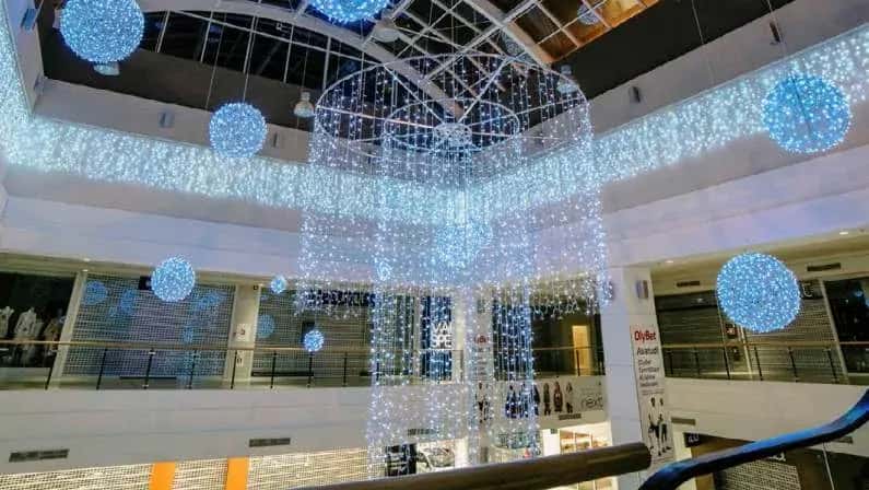 AVM atrium boşluğunda mavi ışık toplarıyla birlikte sarkan dev katmanlı şelale avize