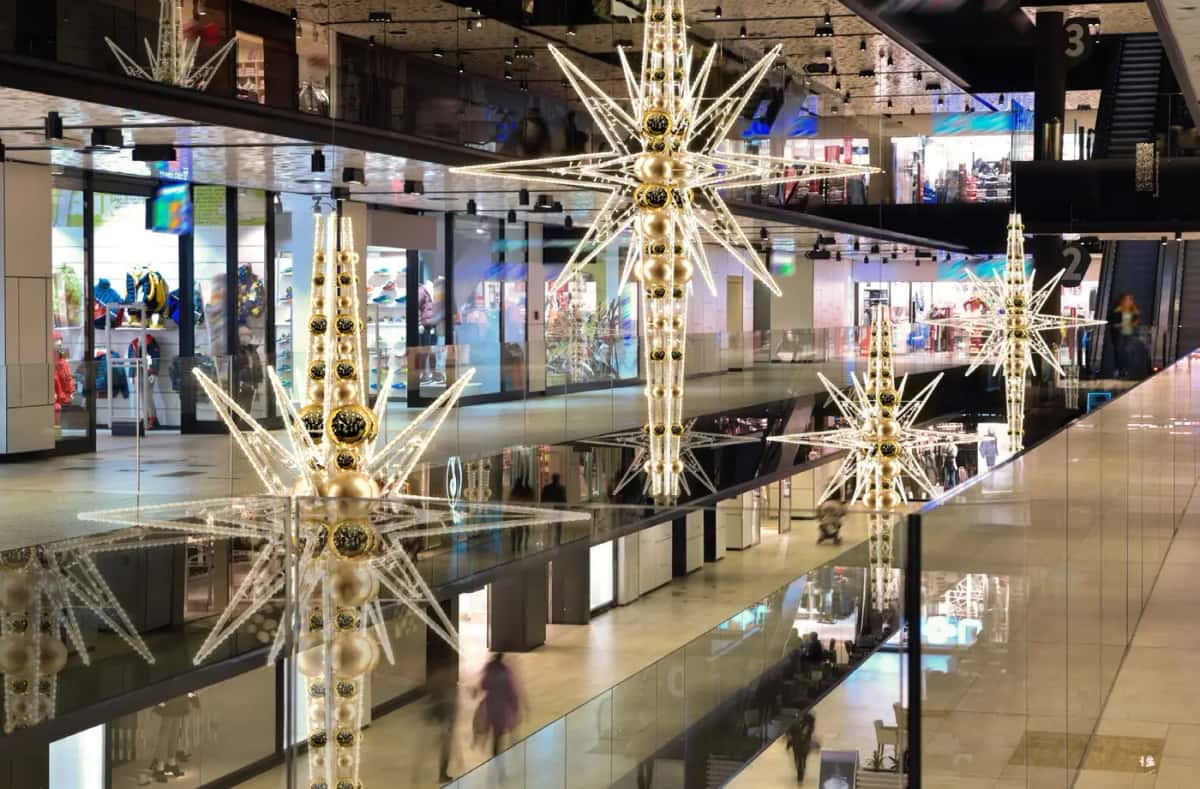 Alışveriş merkezi boşluğunda altın toplu, sivri uçlu asma LED yıldız yapıları