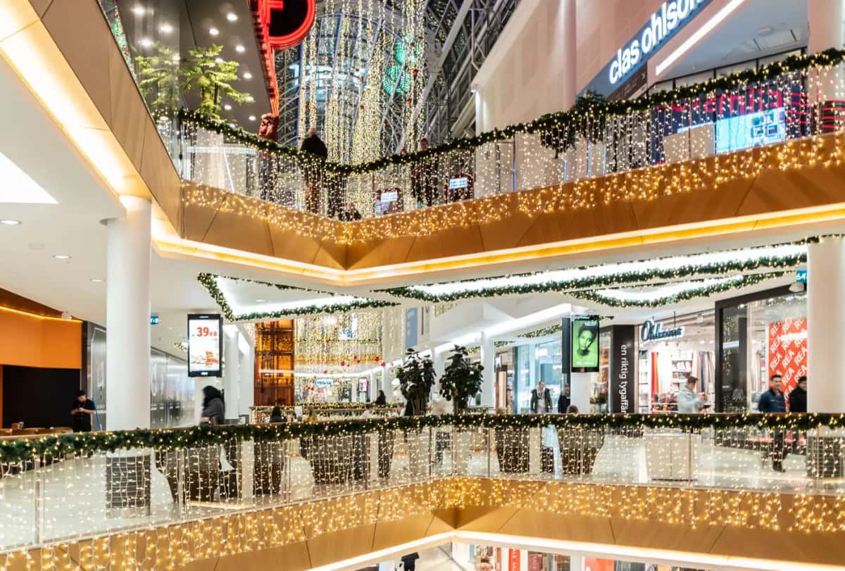 Çok katlı alışveriş merkezinde balkon korkuluklarından sarkan sıcak beyaz perde ışık ve yeşil garland