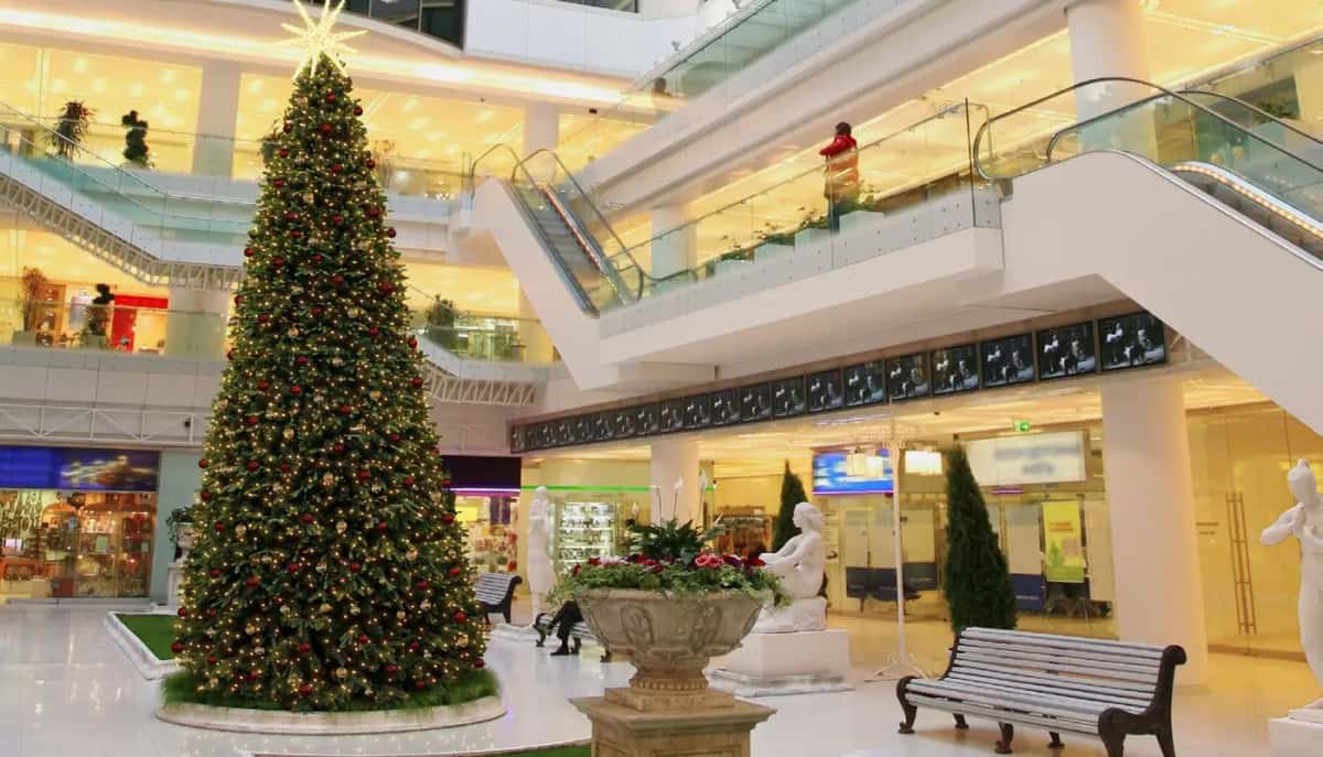 Alışveriş merkezi atriumunda yürüyen merdiven önünde süslenmiş tepesi yıldızlı dev yılbaşı ağacı