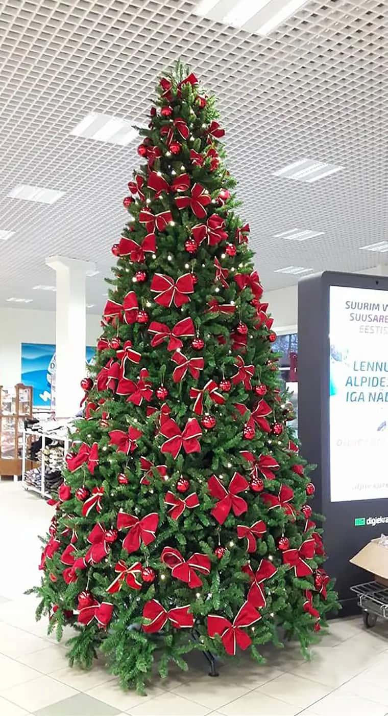 Alışveriş merkezi içinde kırmızı fiyonklarla süslenmiş uzun yılbaşı ağacı
