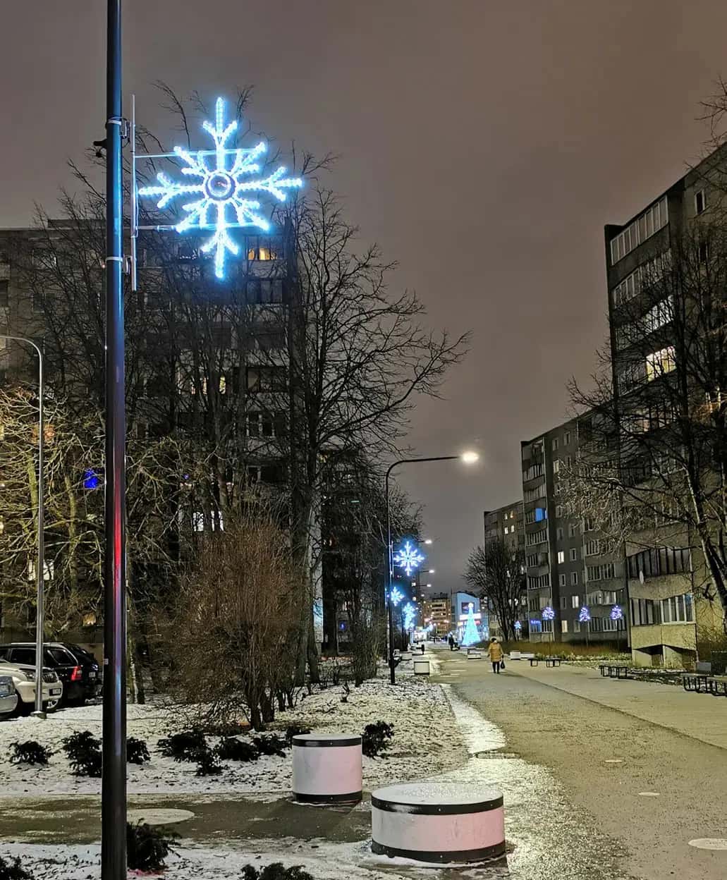 Apartman önündeki yaya yolunda direk tepesinde mavi kar tanesi, karlı gece