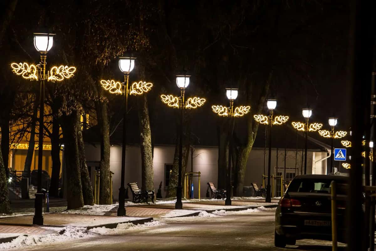 Caddede sıralı fenerli direklerin üstünde altın sarısı yaprak biçimli LED süsler, gece