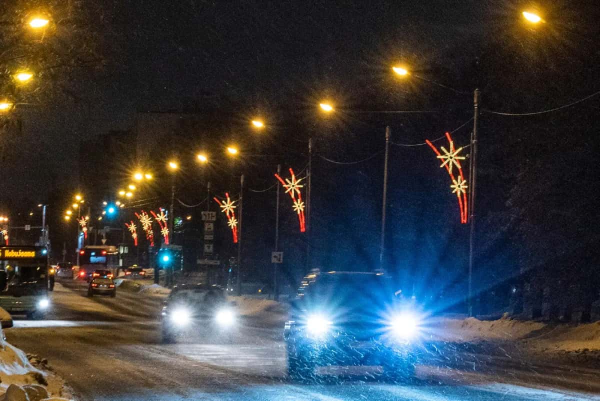 Kar yağan bulvarda lamba direklerinde kırmızı yıldız motifleri, gece