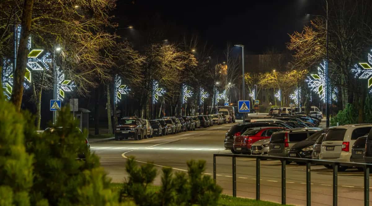 Otoparkın yanındaki yolda sıralı direklerde soğuk beyaz motifler, gece