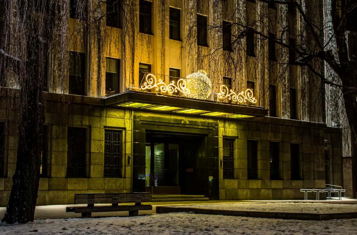 Resmi bina girişinin üstünde kıvrımlı altın sarısı ışık süsü, binada sarı aydınlatma, gece