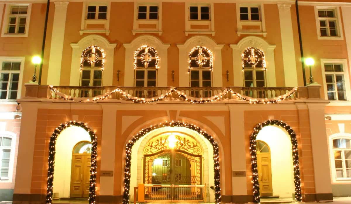 Pembe tarihi bina cephesinde kemer girişlerde ışıklı garland ve pencere süsleri, akşam