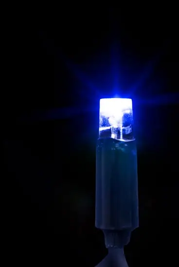 Siyah fonda koyu gövdeli, ışın saçan mavi yanan tek LED lamba