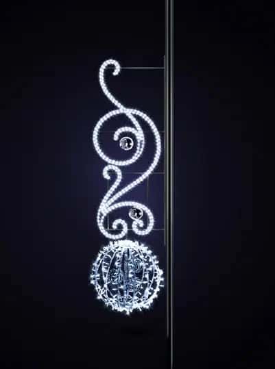 Koyu fonda direğe monte spiral kıvrımlı beyaz LED motif, altta ışıklı küre
