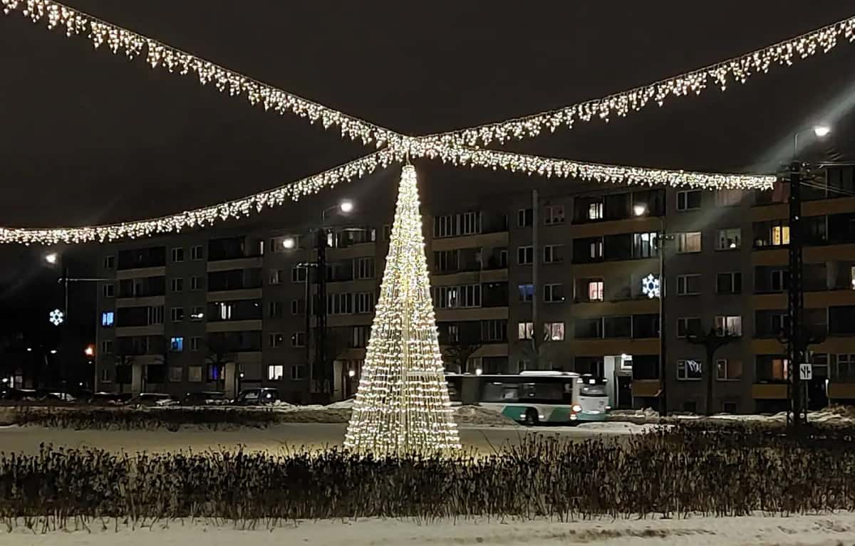 Apartmanların önünde sıcak beyaz LED koni ağaç, ucundan uzanan sarkıt ışık hatları, gece