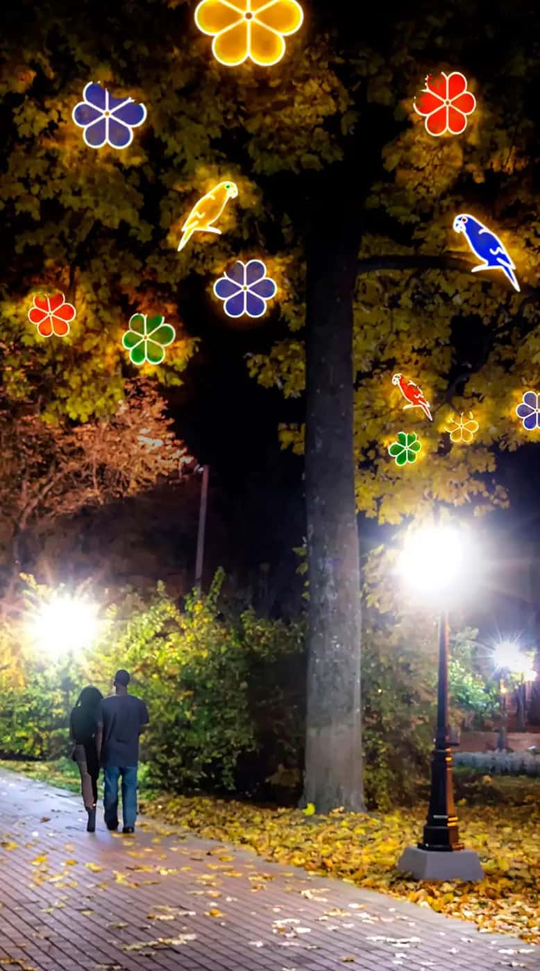Park yolunda gece, sonbahar ağacına asılmış renkli LED çiçek ve kuş figürleri