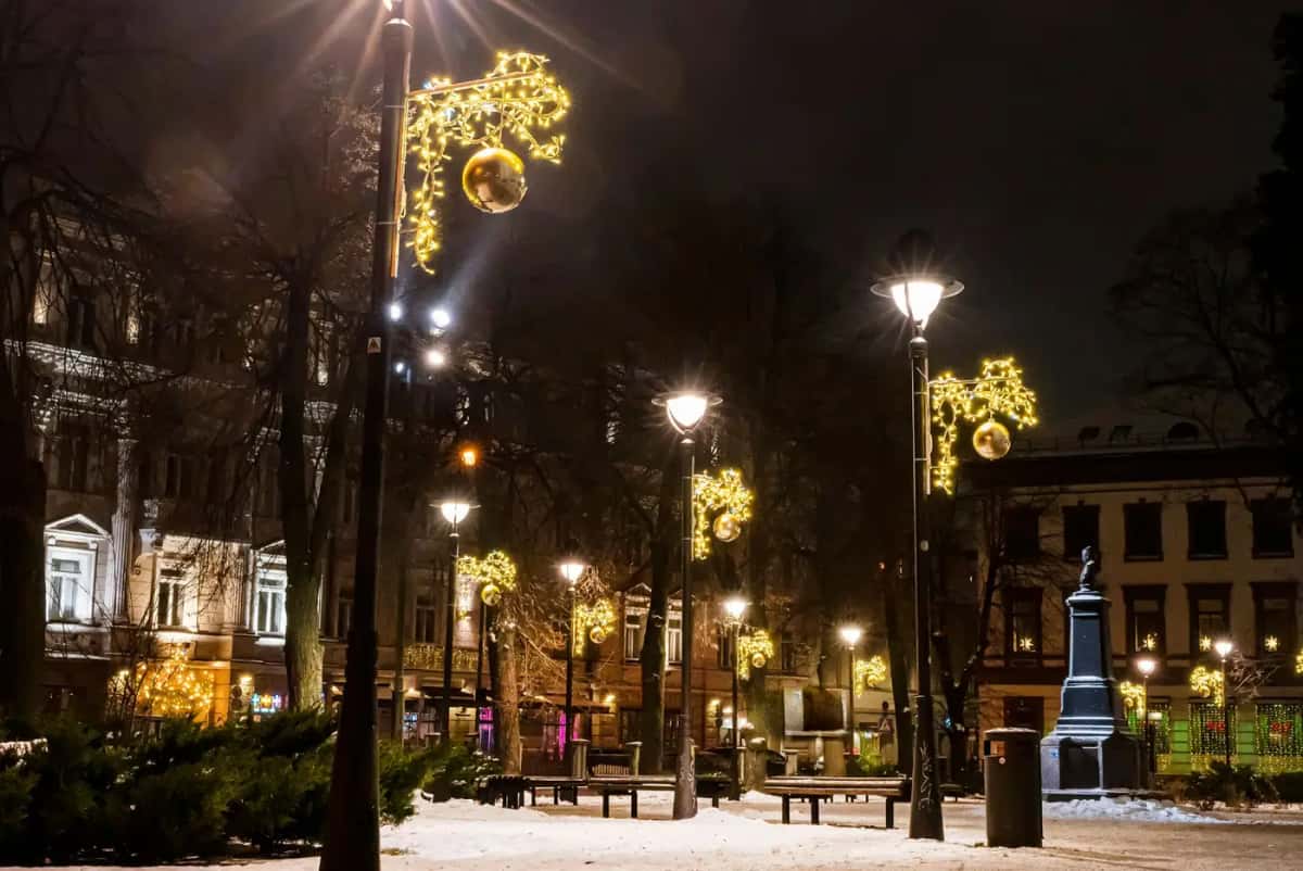 Karlı park yolunda lamba direklerinde altın nota motifleri, gece
