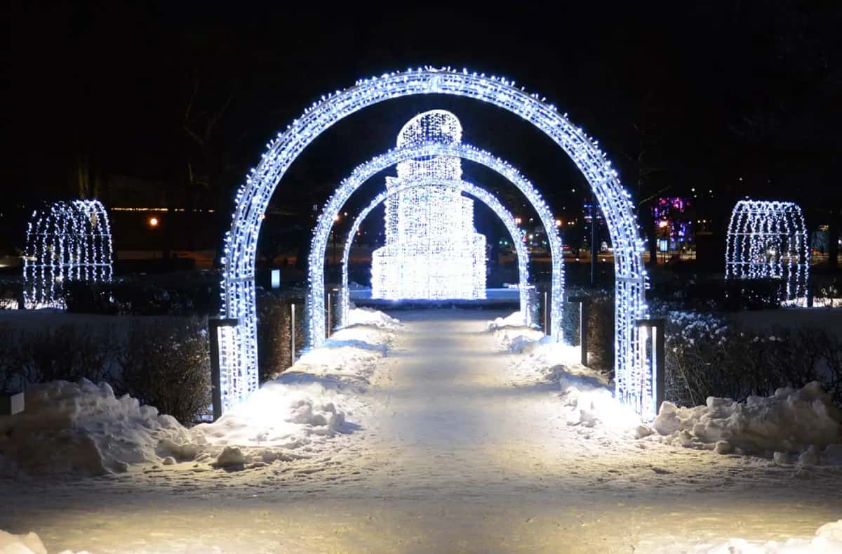 Karlı park yolunda üst üste kemerli soğuk beyaz LED ışık tüneli, gece