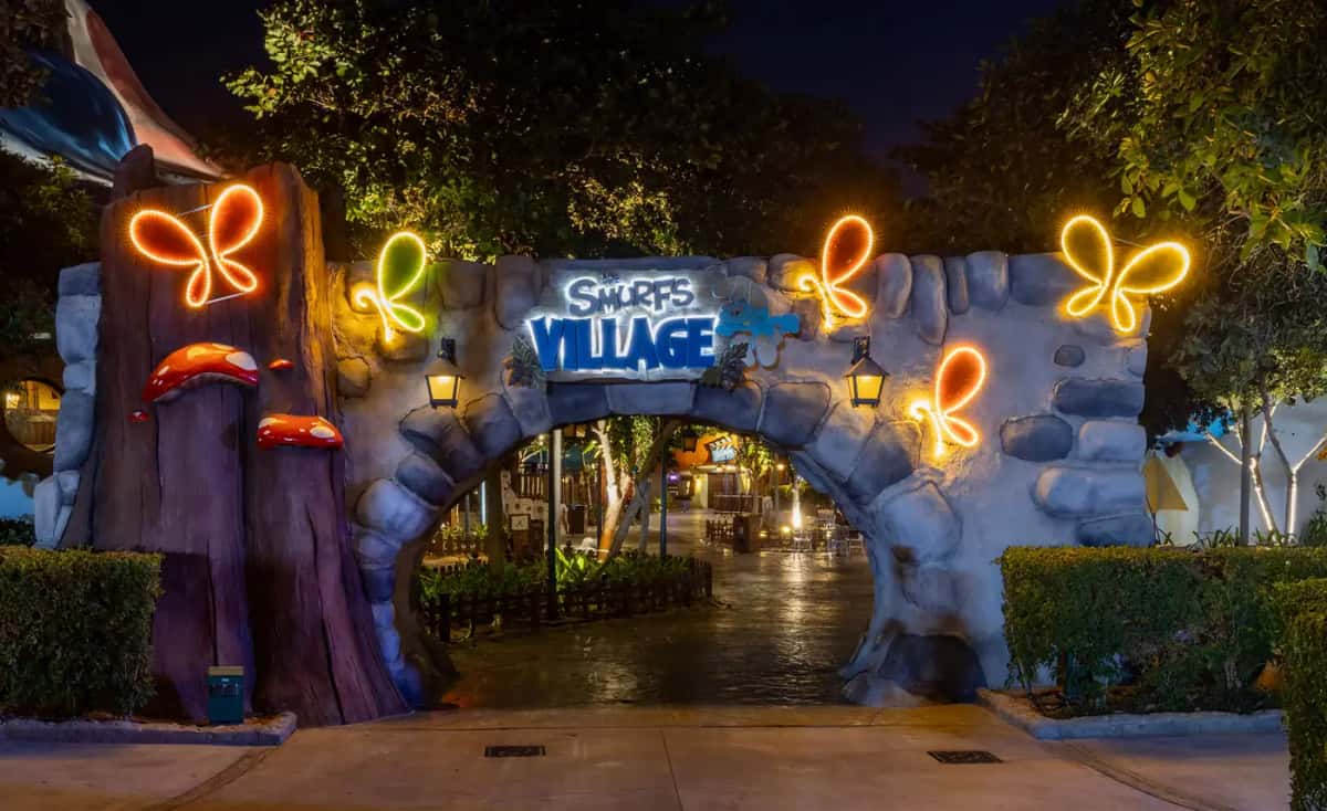 Taş kemerli tema parkı girişinde turuncu ve yeşil LED kelebek motifleri, gece
