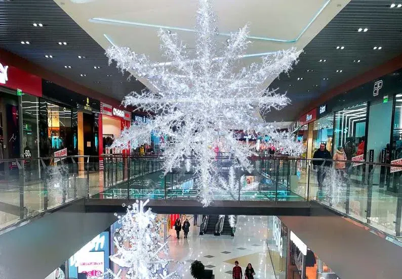 AVM atriumunun tavanından sarkan dev beyaz kar tanesi figürü, iki kat arası boşlukta
