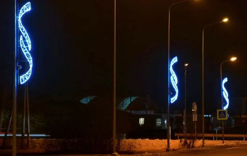 Cadde direklerinde sıralı mavi ve altın LED S-kıvrımlı şerit motifler, kar yağışlı gece