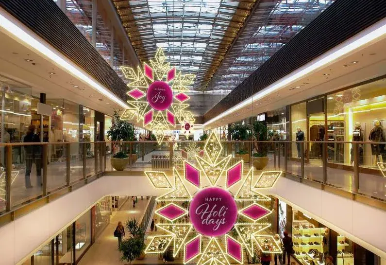 AVM galerisinde tavandan sarkan mesaj yazılı altın kar tanesi figürleri